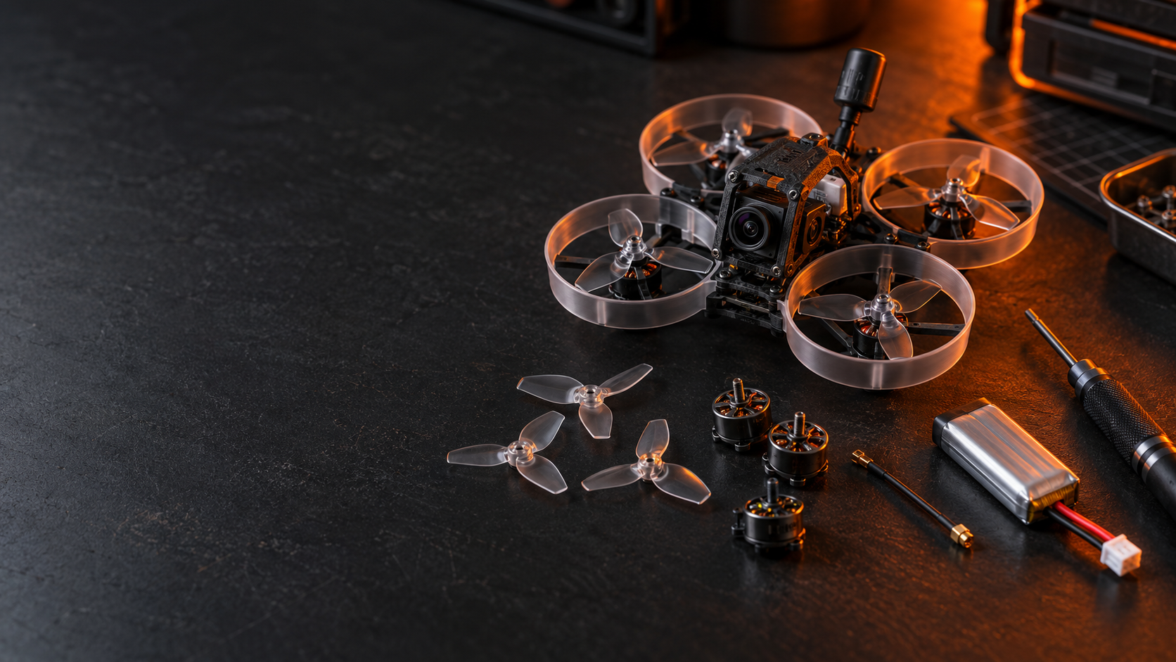 A tiny FPV whoop and repair parts arranged on a dark workbench